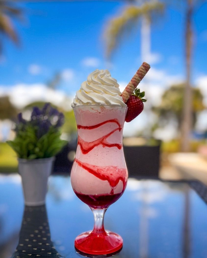 Strawberry milkshake topped with cream and a wafer
